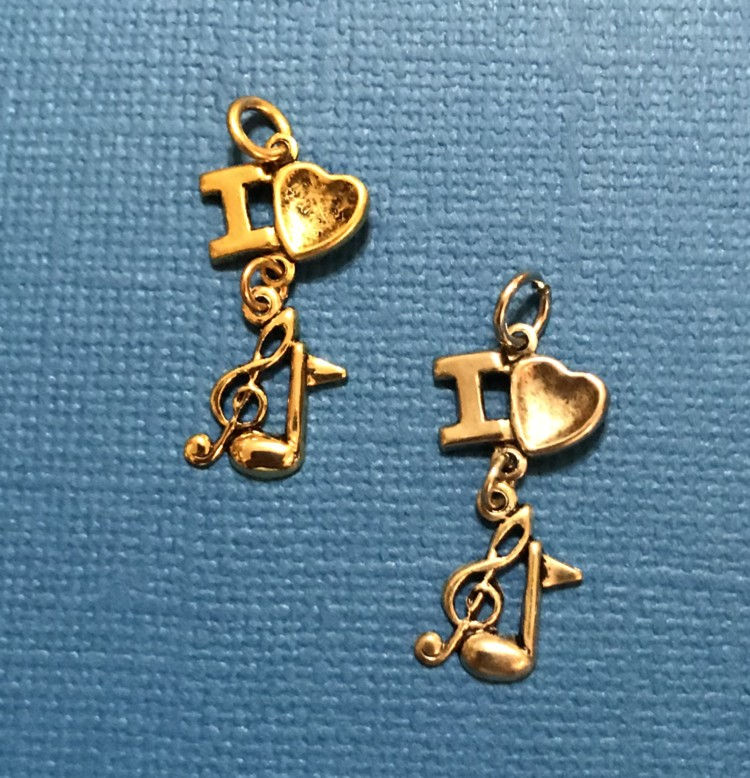 Thumbnail: Two I love music charms, one silver, one gold, with a music note and a trble clef hanging from the charm.