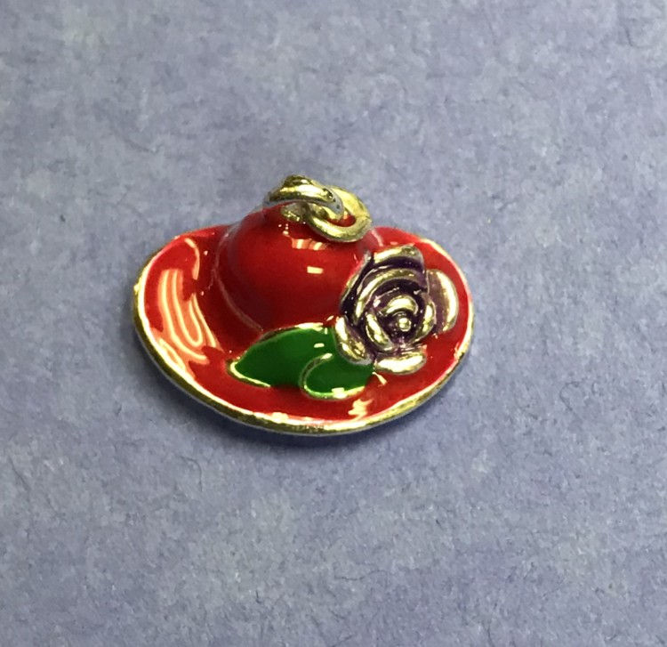 A stylish red hat charm featuring an arrangement of flowers and leaves, adding a touch of nature-inspired elegance.