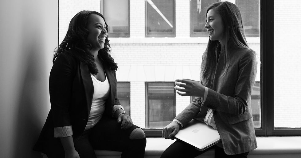 two ladies at work, facing eachother and smiling and talking