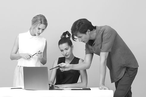 a group of people looking at a laptop and pointing at it with their pens