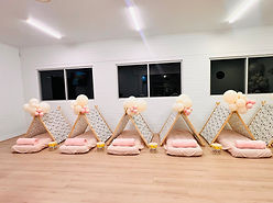 Indoor children's party setup with six decorated teepee tents and matching floor cushions