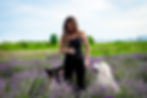 Une éducatrice canine en interaction avec deux chiens dans un champ fleuri, représentant un cadre naturel propice à l'éducation canine.