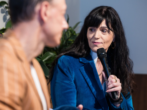 Justine Martin in her blue coat holding microphone.