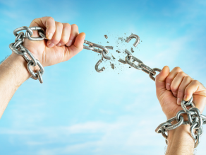 Male hands break the chains on clear blue sky background with copy space. Freedom concept.