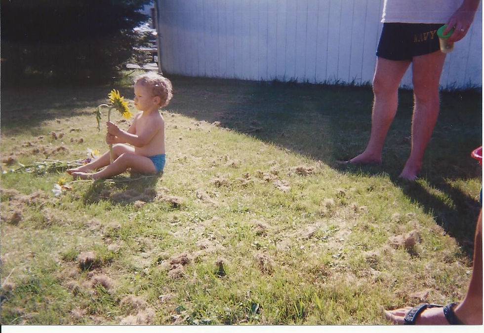 Baby me post adoption from Kharkiv, Ukraine—about 4 months into living in Maine. looking into my native country's national flower with the sunrays reflecting off the petals onto my face
