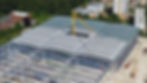 A large warhouse under construction with a yellow crane poking out the middle of the roof.