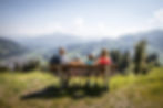 Familie sitzt auf Bank und blickt auf die Kitzbueheler Alpen