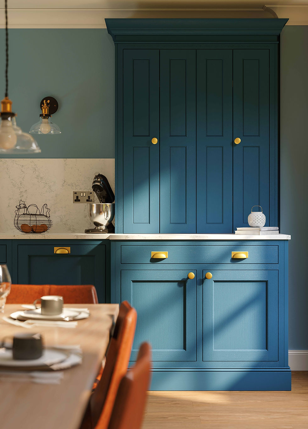 Blue kitchen with cabinets, marble counter, mixer, wire basket with eggs, and small lantern. Warm sunlight creates a cozy mood.