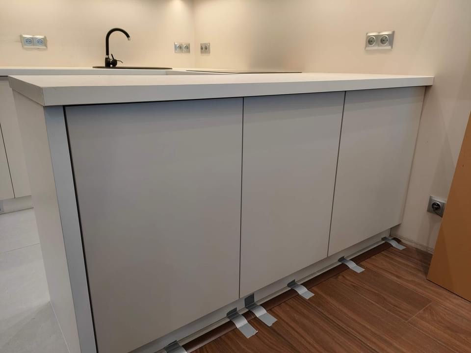 Kuchnia w zabudowie w kształcie litery "U", z czego jeden bok zabudowy niskiej kuchni funkcjonuje jako wyspa oddzielająca salon od kuchni.