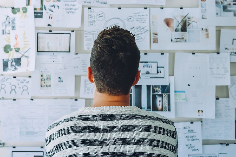 a man looking at a wall full of complex charts and papers
