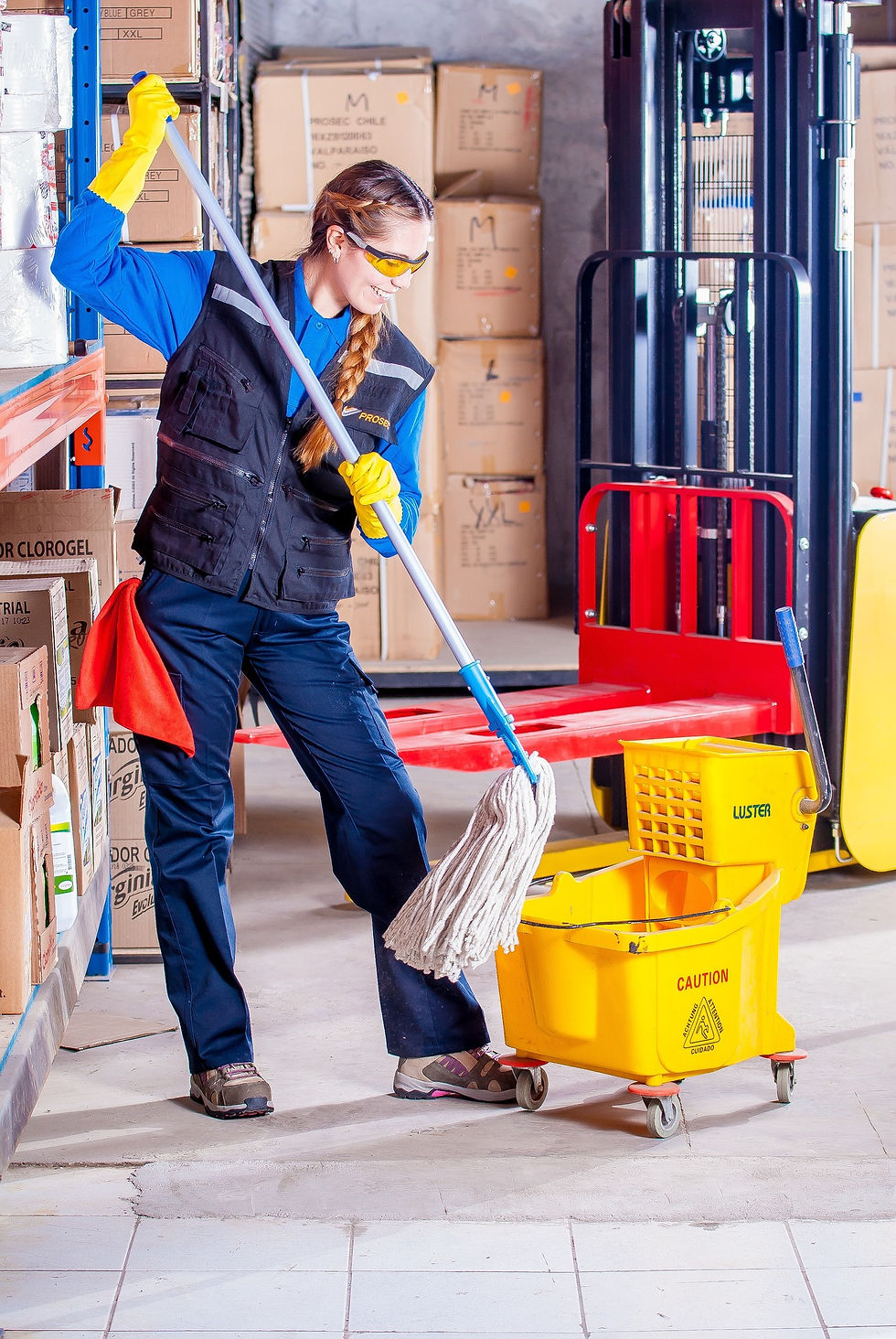 a cleaning women smiling and dipping her mop into a mop bucket