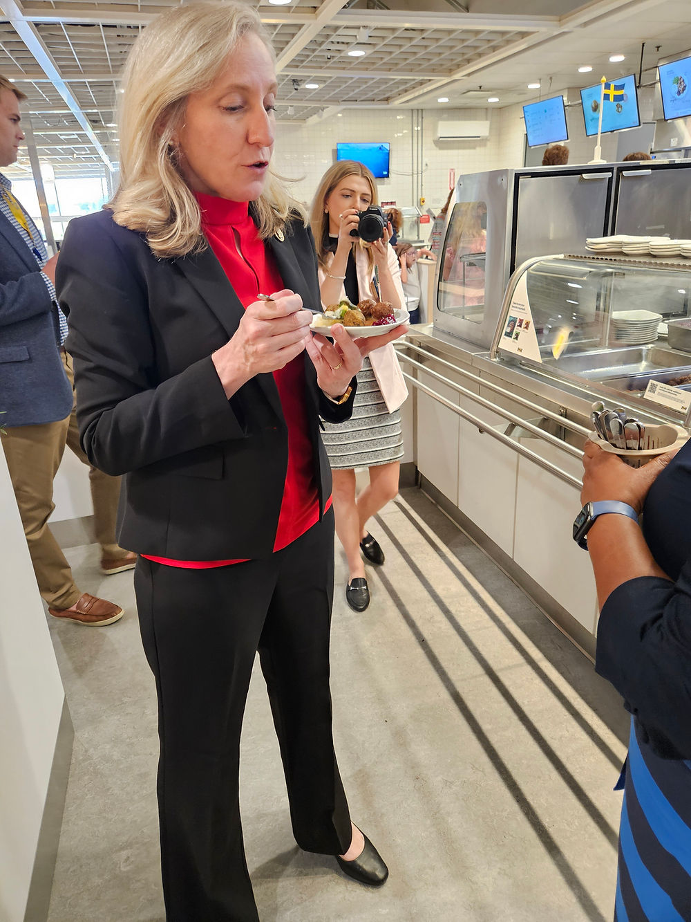 Woman in a red shirt and black blazer samples food