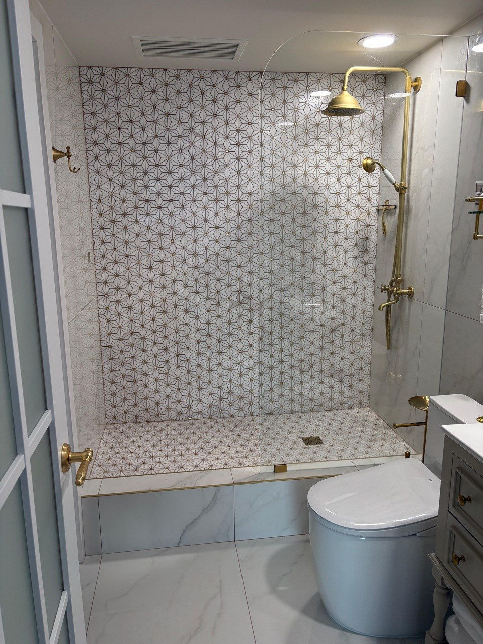 Elegant bathroom with gold fixtures and patterned tiles.
