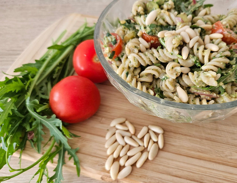 Nudelsalat auf einem Brett mit Rucola, Tomaten und Nüssen