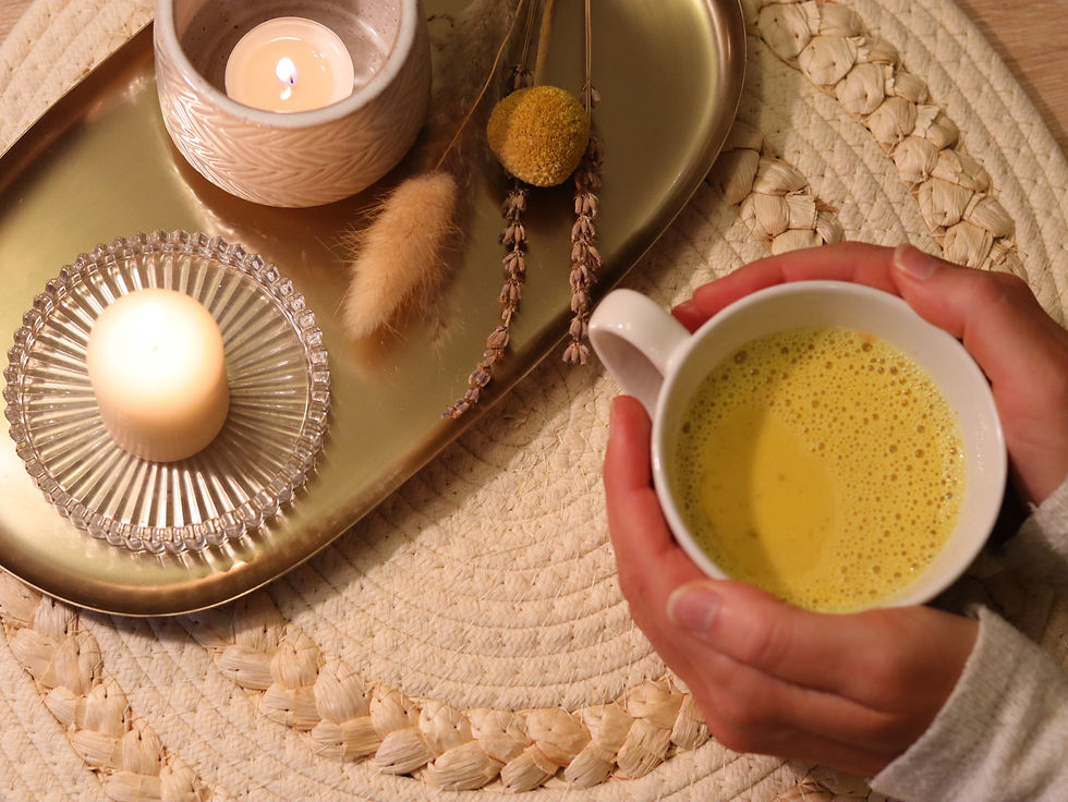Kerze, Trockenblumen und eine Tasse Goldene Milch Kurkuma Latte