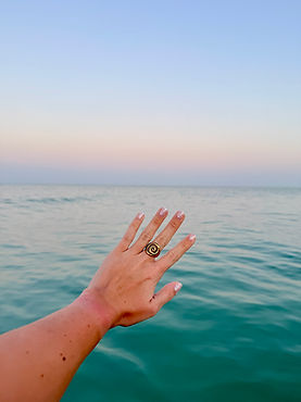 Sunrise on the ocean with hand that has gold jewlery