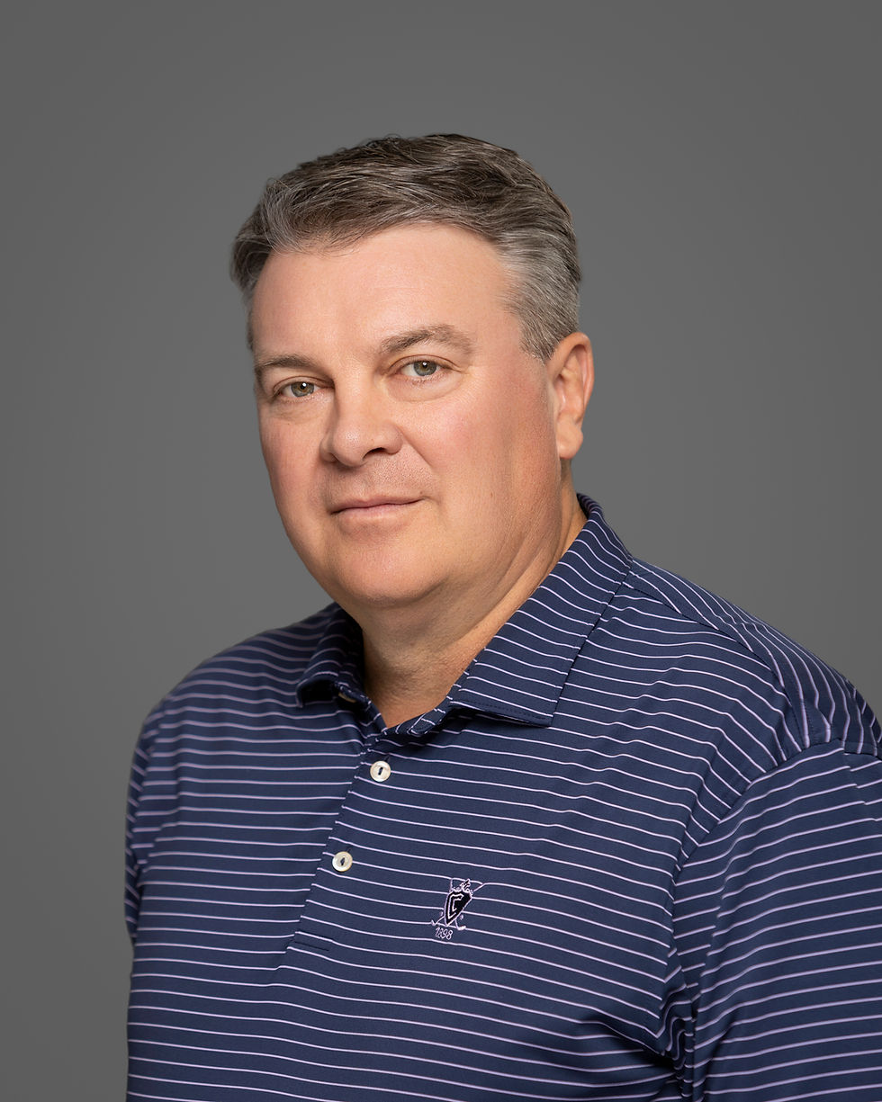 Professional headshot of a man in a navy striped polo shirt against neutral gray backdrop, demonstrating proper body angle and shoulder posture.