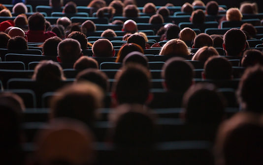 a cinema screen seating full of people 