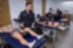 Sports Rehab room with 3 clinicians and patients doing treatments such as cupping and diagnostic ultrasound