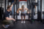 Female doing ring push-ups on squat rack with observer