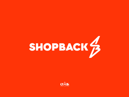 White "SHOPBACK" text with lightning bolt logo on bright orange background. Below, "COINS TO CASH DOLLARS" logo.