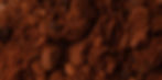 A close-up image of used coffee grounds, showcasing their rich, dark brown color and coarse texture with small clumps and particles.