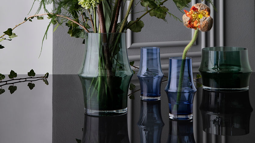 green and blue vases on a black table with a white wall