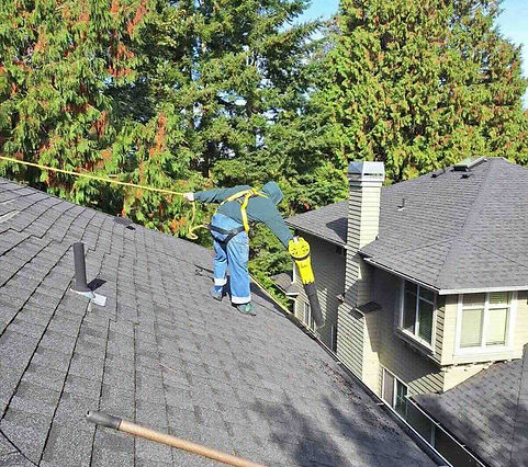 Husser technician using rope & harness to access 3rd story gutters with a leaf blower