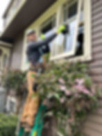 Husser technician cleaning storm windows on a Queen Anne single story home.