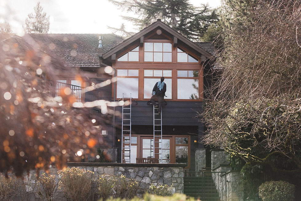 Husser technician on a ladder cleaning the windows at a luxury Mercer Island Property