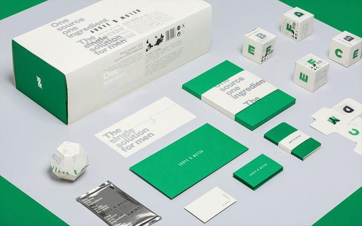 Green-and-white packaging mockups and paper items on a gray surface, with printed text and cube boxes in a clean studio layout