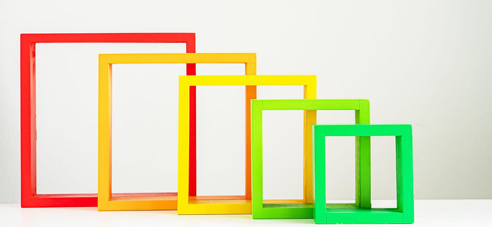 Colorful empty frames in red, orange, yellow, and green are lined up in descending size on a white surface against a plain light background.