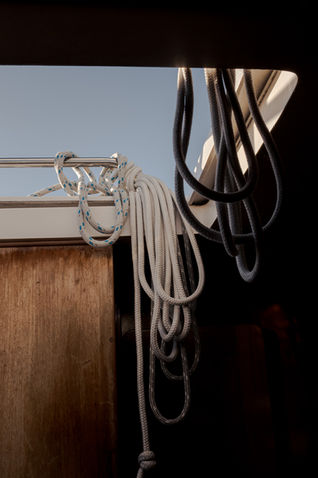Ropes dangling into the hull of a sailing vessel in sunset light - Sail San Diego