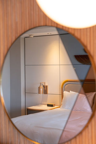 Hotel Imagery - Shot of bed and side table through a creative mirror on the opposite wall