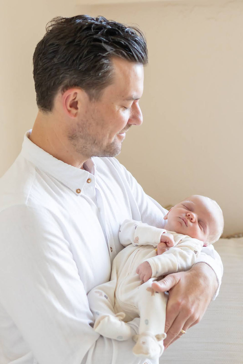 A man holds a newborn baby in his arms and looks down at him