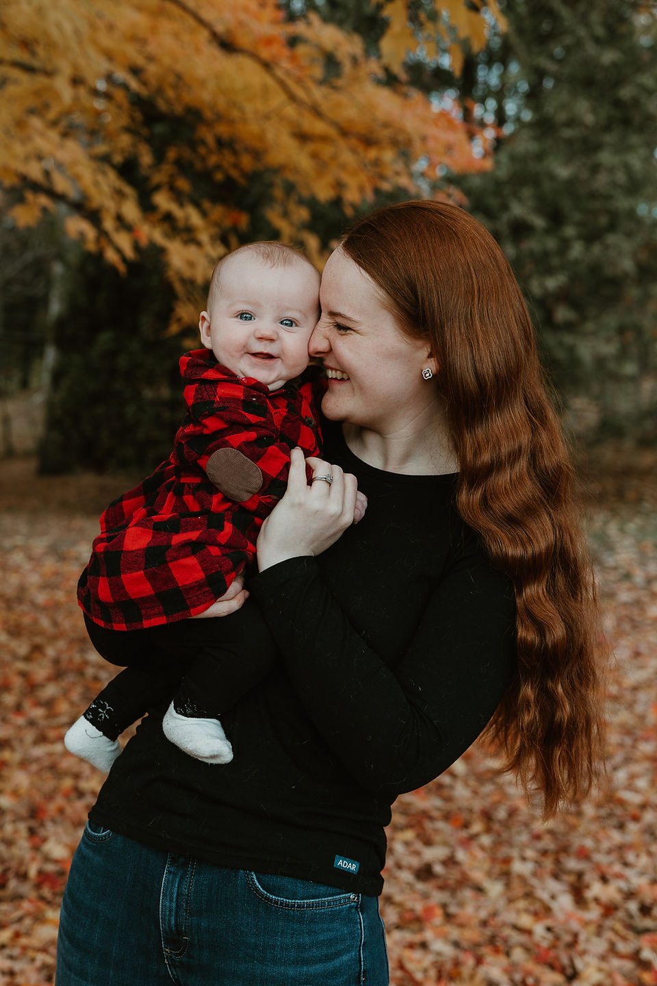 A woman laughs as she holds a smiling baby in her arms