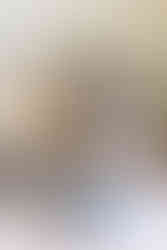 A woman sits on the floor and a young girl sits in her lap and behind them is a couch and floral arrangement