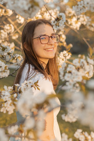 A woman stands amongst the flowering branches of a tree