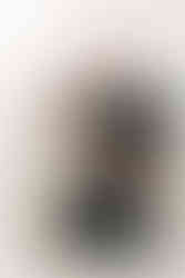 A man kneels on the floor as he holds a newborn baby and a young boy stands beside him