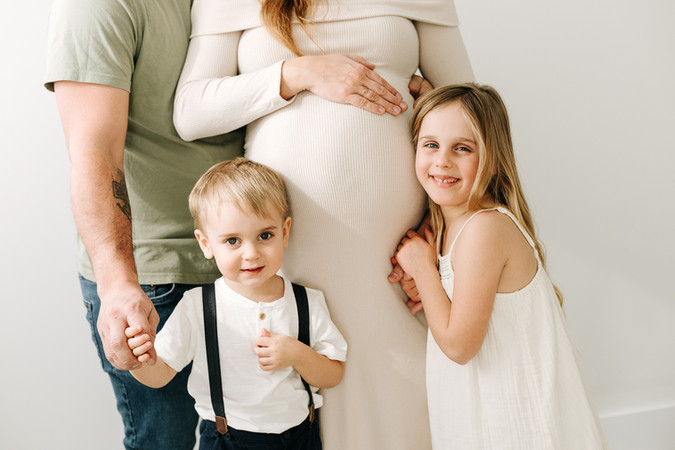 torso of mom and dad with son and daughter standing in front and smiling 
