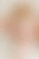 overhead shot of baby girl sitting on the floor in pink dress with bow in her hair