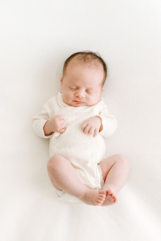 A newborn baby in a long sleeve white onesie