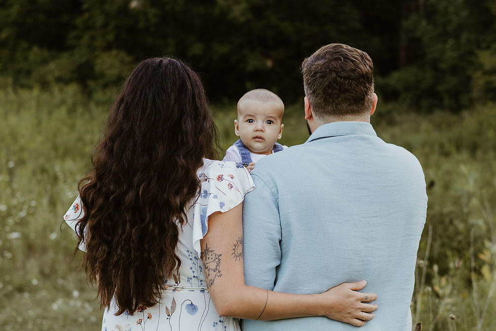 The back of a man and woman as they stand and hold a baby up between them
