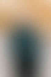 An older man stands and smiles under a tree in fall