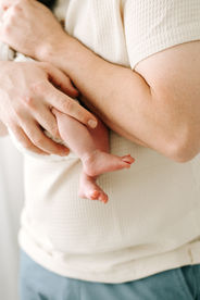 A man's arms as he holds a newbonr baby