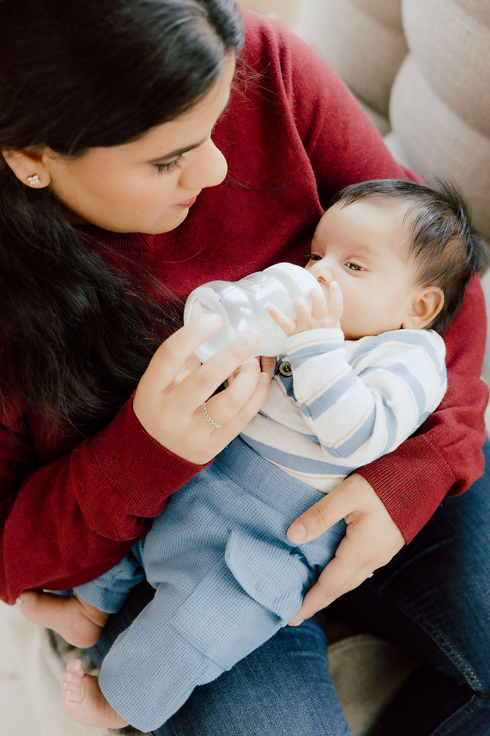 A woman holds a baby in her arms and feeds him with a bottle