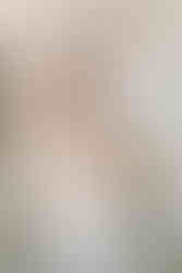 A woman sits on a stone bench with a toddler boy on her lap and another boy standing beside her with his arms around her