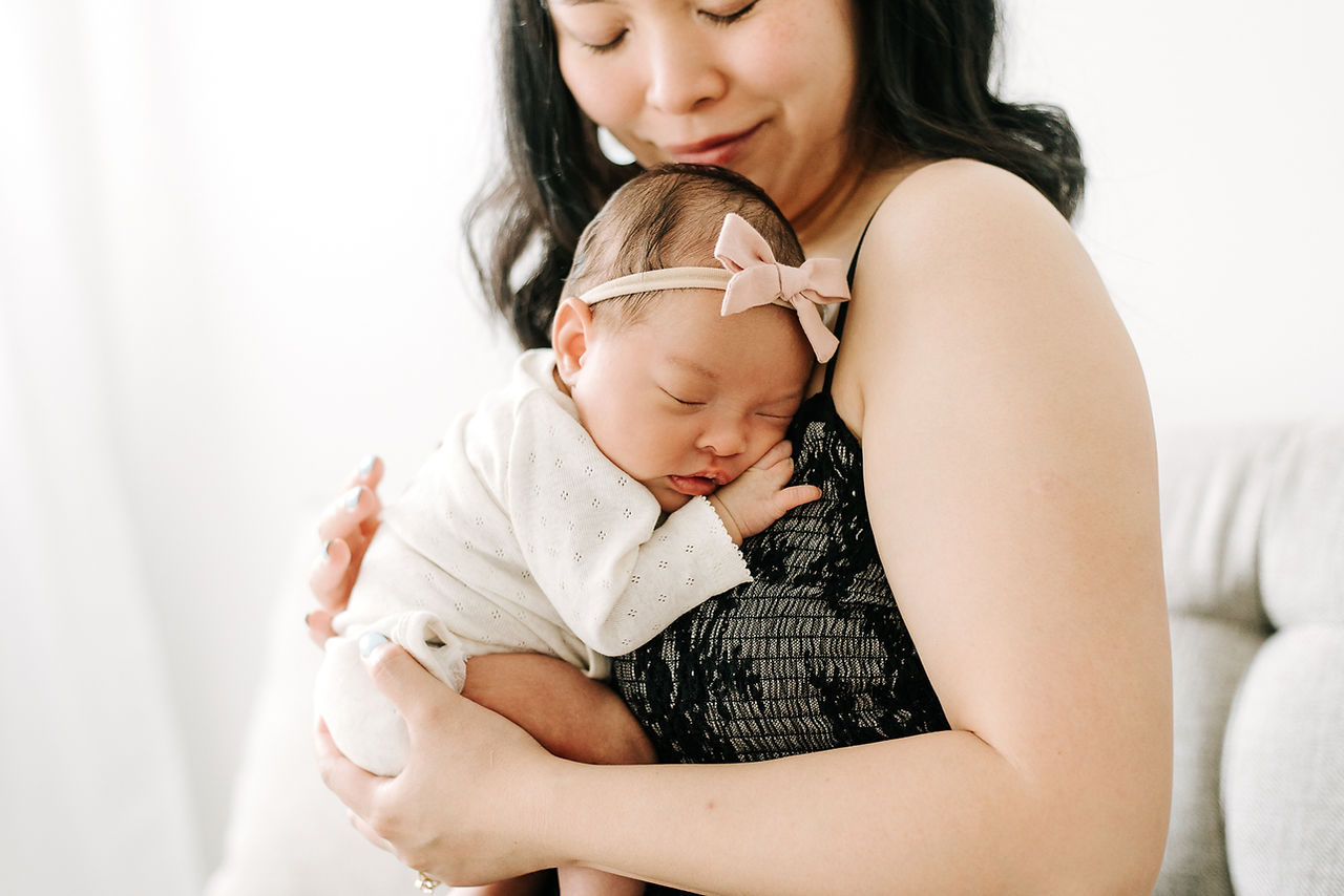 A woman cradles a newborn baby to her chest and looks down at her