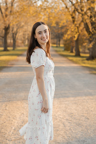 A womans twirls and smiles on a path under trees