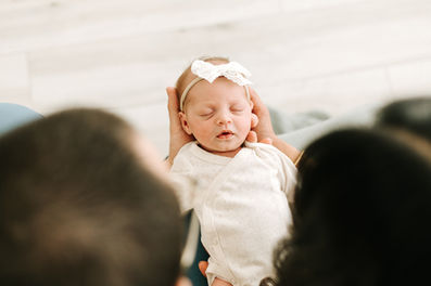 the back of a man's and woman's head as they look down at a newborn baby